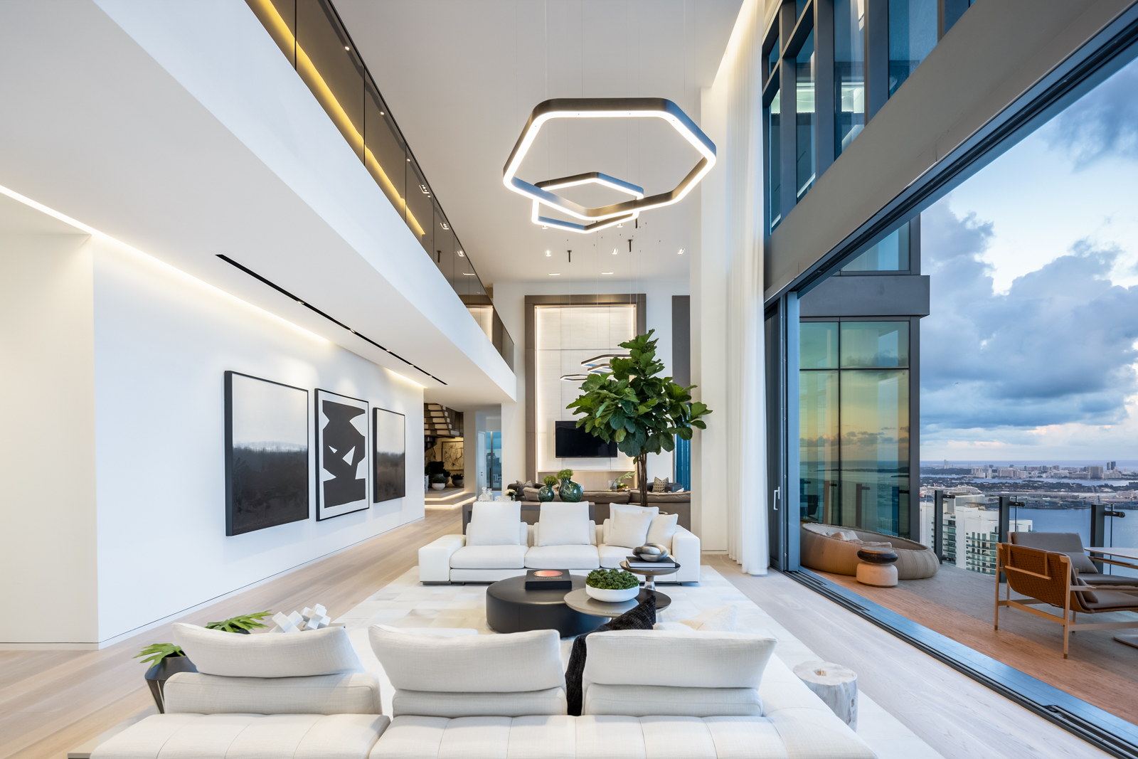 Contemporary double-height living room at Echo Penthouse featuring neutral furnishings, geometric lighting, and a curated modern art collection.