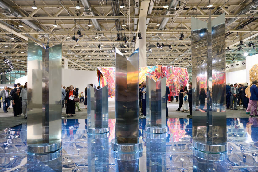 Polished metal sculptures by Heinz Mack presented by Almine Rech at Art Basel 2025, reflecting light across a mirrored blue floor installation.